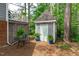 Backyard shed offers storage space and is framed by a border of tall trees and manicured shrubs at 1813 Carrington Dr, Raleigh, NC 27615