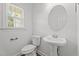 Bathroom with pedestal sink, toilet, oval mirror, and natural light at 185 Keller Dr, Clayton, NC 27520