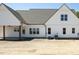 Rear view of a white farmhouse home with a dark roof, patio with ceiling fan, and AC units at 188 Banner Elk Rd, Benson, NC 27504