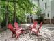 Serene backyard featuring a fire pit surrounded by comfortable red Adirondack chairs and lush landscaping at 203 Chilcott Ln, Apex, NC 27502