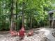Backyard fire pit area with four red chairs, surrounded by trees and lush greenery at 203 Chilcott Ln, Apex, NC 27502