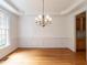Elegant dining room with hardwood floors, wainscoting details, tray ceiling, and a stylish chandelier at 203 Chilcott Ln, Apex, NC 27502