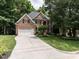 Beautiful brick home with a spacious driveway, lush green lawn, and mature trees offering shade and curb appeal at 203 Chilcott Ln, Apex, NC 27502