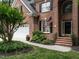 Close-up of a classic brick home showcasing an arched doorway, beautiful landscaping, and an attached two-car garage at 203 Chilcott Ln, Apex, NC 27502