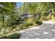 Beautiful home exterior with a stone retaining wall, lush landscaping, and a curved driveway at 203 Old Forest Creek Dr, Chapel Hill, NC 27514