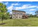 Three-story home's back exterior showcasing a wooden deck, complemented by a lush, green lawn and mature trees at 208 Bridle Boast Rd, Cary, NC 27519