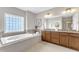 Well-lit bathroom features a soaking tub, tile surround, a privacy window, and dual sinks at 208 Bridle Boast Rd, Cary, NC 27519
