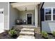 Inviting covered front porch featuring stone steps, modern chairs and planters, perfect for relaxing at 220 Purslane Dr, Franklinton, NC 27525
