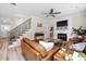 Open living room with hardwood flooring, white painted fireplace, stairs to the upper level, and a ceiling fan at 220 Purslane Dr, Franklinton, NC 27525