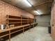 Basement workshop area featuring ample shelving, brick walls, concrete flooring, and workspace for projects at 2228 Walker Ave, Burlington, NC 27215