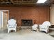 Basement brick fireplace flanked by wicker chairs and concrete floors, creating a cozy and inviting space at 2228 Walker Ave, Burlington, NC 27215