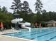 View of swimming pool with slide, lounge seating, poolside umbrellas, and lifeguard chair at 2361 Rainy Lake St, Wake Forest, NC 27587