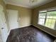 An empty room with dark wood floors, an exterior door and a white interior door requiring some renovation at 2377 Vinson Rd, Clayton, NC 27527