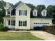Two-story yellow home with black shutters, attached garage, and visible fire damage near the front left upper window at 2377 Vinson Rd, Clayton, NC 27527