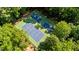 Aerial view of well-maintained tennis courts surrounded by lush greenery, perfect for recreational activities in a natural setting at 2409 Beechview Ct, Raleigh, NC 27615