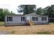 Charming single-story home features gray siding, black shutters, a welcoming front porch and lovely landscaping at 2668 Bodie Currin Rd, Oxford, NC 27565