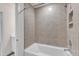 Bright bathroom with a clean white tub and a tiled shower wall with a small shelf at 30 Sawtooth Oak Ln, Youngsville, NC 27596