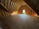 Unfinished attic space with exposed beams and a window at the far end at 332 Inspiration Way, Fuquay Varina, NC 27526