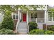 Close up of covered front porch with white railings, a red door, seating, and lush landscaping at 3923 Napa Valley Dr, Raleigh, NC 27612