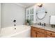 A bright bathroom features a tub with tile surround, a granite countertop, and a wood vanity at 4020 Gumleaf Dr, Apex, NC 27539