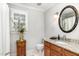 Updated bathroom featuring granite counters, wooden cabinets, and a floral-framed vanity mirror at 4020 Gumleaf Dr, Apex, NC 27539