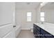 Bright bathroom features a single sink vanity with navy blue cabinets, light tile flooring, and a shower-tub combo at 408 Longleaf Glen Lane, Zebulon, NC 27597
