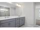 Bathroom featuring gray vanity with double sinks, large mirror, and glass-enclosed shower with marble-patterned tile at 408 Longleaf Glen Lane, Zebulon, NC 27597