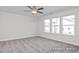 Spacious bedroom with neutral carpet, ceiling fan with lights, and three windows with a backyard view at 408 Longleaf Glen Lane, Zebulon, NC 27597