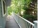 Wooden porch with white railings overlooking natural landscaping and lush greenery at 4144 Fairport Rd, Kittrell, NC 27544