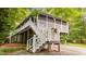 Backyard showing the elevated deck with white railings, stairs and surrounding trees at 4144 Fairport Rd, Kittrell, NC 27544
