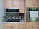 Modern kitchen with stainless steel appliances, mosaic backsplash, and light wood cabinetry, perfect for cooking enthusiasts at 4144 Fairport Rd, Kittrell, NC 27544