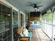 Relaxing screened-in porch with outdoor seating, a bed swing, ceiling fan, and a mounted TV at 4144 Fairport Rd, Kittrell, NC 27544