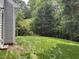 Manicured backyard featuring vibrant green lawn, partial fence, and a wooded landscape at 431 Mayview Dr, Creedmoor, NC 27522
