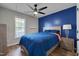 This bedroom features hardwood floors, a ceiling fan, and is brightly lit by a window and bedside lamp at 5316 Tanglewood Pine Ln, Raleigh, NC 27610