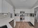 Well-lit kitchen features white cabinets, stainless steel appliances, and quartz countertops at 5316 Tanglewood Pine Ln, Raleigh, NC 27610