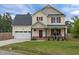 Charming two-story home featuring a red door and shutters, a well-manicured lawn, and an attached two-car garage at 576 Prairie Ln, Lillington, NC 27546