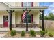 Inviting covered front porch with rocking chairs, flag, and decorative stonework at 576 Prairie Ln, Lillington, NC 27546
