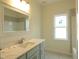 Light and airy bathroom featuring updated cabinetry, a bright mirror, and a view from the window at 614 Tart Town Rd, Dunn, NC 28334
