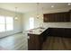 An open kitchen features dark wood cabinets, an island with a sink, white counters, and stylish pendant lighting at 614 Tart Town Rd, Dunn, NC 28334