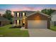 Beautiful two-story home at dusk with brick accents, large windows, manicured lawn, and an attached garage at 634 Cotton Brook Dr, Fuquay Varina, NC 27526