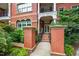 Charming brick building entrance featuring a covered porch, stone pillars, and landscaped greenery at 710 Independence Pl # 103, Raleigh, NC 27603