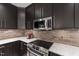Close-up of a modern kitchen featuring marble countertops, stainless steel appliances, and dark cabinetry at 710 Independence Pl # 103, Raleigh, NC 27603