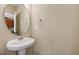 Chic half bath featuring a pedestal sink, oval mirror, and neutral wall color scheme at 717 Samuel Cary Dr, Cary, NC 27511