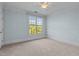 Light-filled bedroom with neutral carpet, light blue walls, and a large window at 735 Portstewart Dr, Cary, NC 27519
