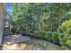 Landscaped backyard with brick paver patio, manicured shrubbery, and a peaceful wooded backdrop at 736 Varina Ln, Fuquay Varina, NC 27526