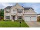 Charming two-story home featuring a well-manicured lawn and a two-car garage with beige siding and dark shutters at 7612 Vista Del Rey Ln, Raleigh, NC 27613