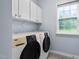 Functional laundry room with modern washer and dryer, overhead cabinets, and natural light at 7612 Vista Del Rey Ln, Raleigh, NC 27613