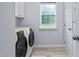 Bright laundry room with modern washer and dryer, a window, and ample storage space at 7612 Vista Del Rey Ln, Raleigh, NC 27613