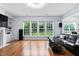 Bright living room with fireplace, large windows overlooking the yard and a modern black leather sofa at 7612 Vista Del Rey Ln, Raleigh, NC 27613