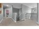 Open hallway with carpet floors leading to staircase with white and wood railing at 784 Cypress Rd, Cameron, NC 28326